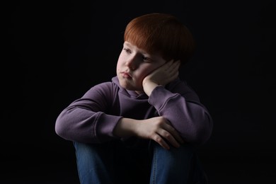 Photo of Portrait of sad little boy on black background