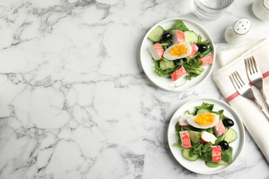 Delicious crab stick salad served on white marble table, flat lay. Space for text