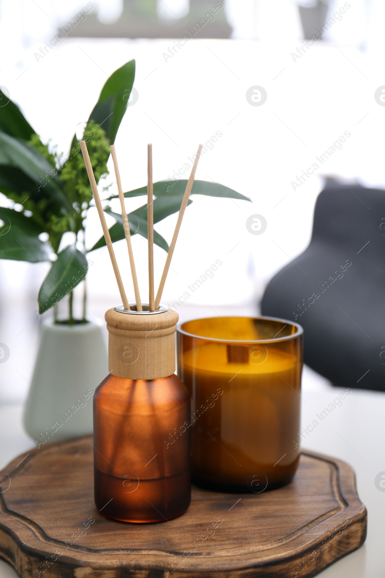 Photo of Reed air freshener and candle on table indoors