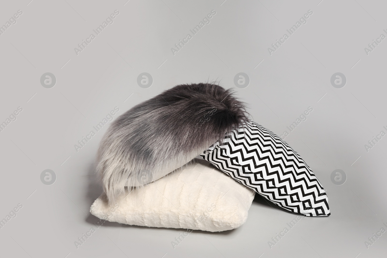 Photo of Pile of stylish decorative pillows on light background