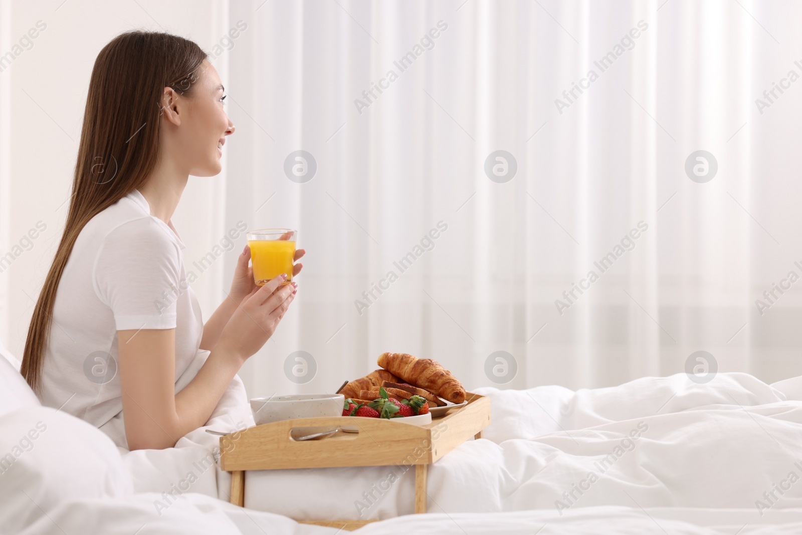 Photo of Smiling woman having breakfast in bed at home. Space for text