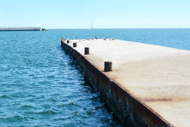 Photo of Beautiful concrete pier in sea on sunny day, space for text
