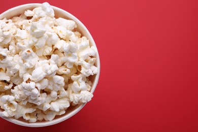 Paper bucket with delicious popcorn on red background, top view. Space for text