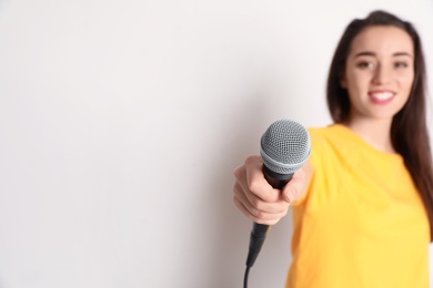 Photo of Young woman holding microphone and smiling on color background. Space for text