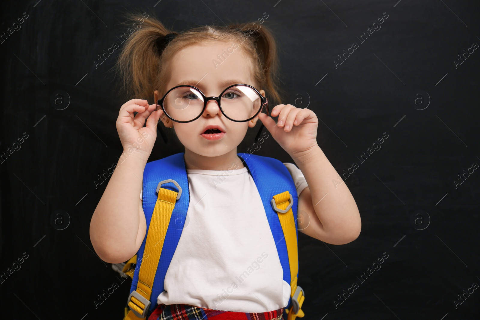 Photo of Cute little child wearing glasses near chalkboard. First time at school