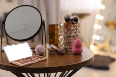 Different beauty products and mirror on wooden table in makeup room, closeup