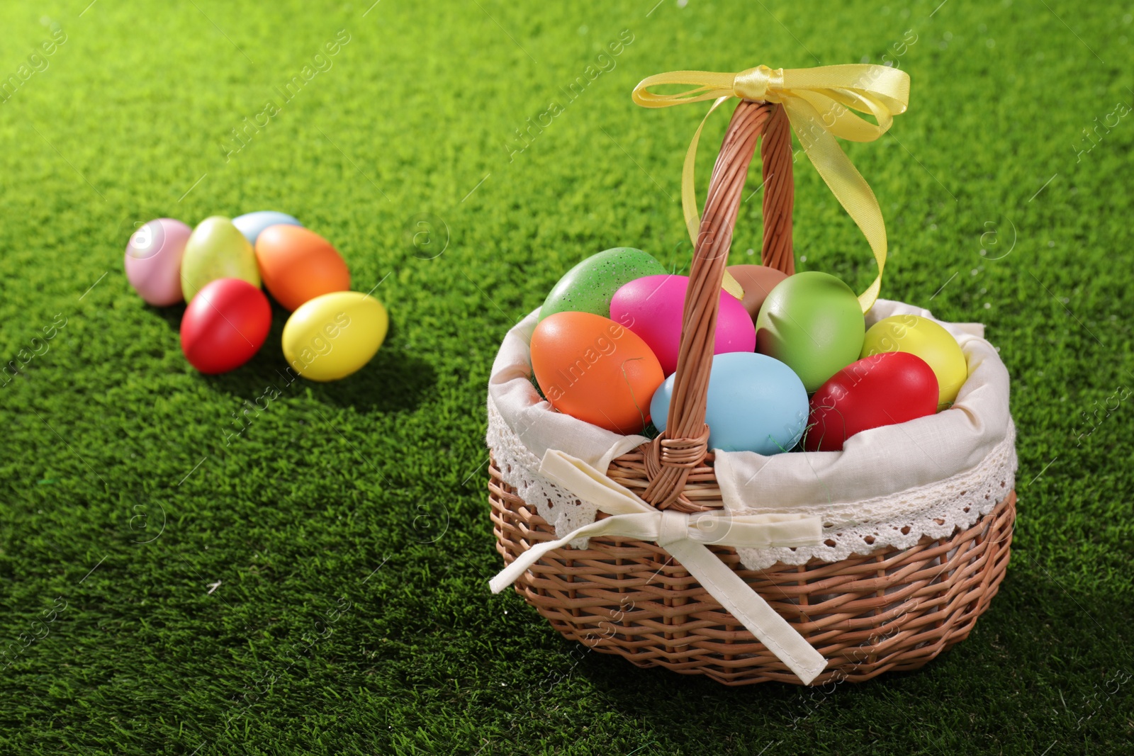 Photo of Easter basket with painted eggs on green grass