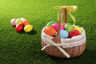 Easter basket with painted eggs on green grass