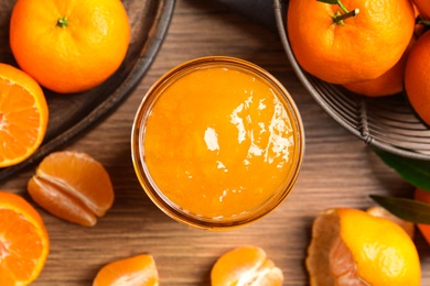 Flat lay composition with delicious tangerine jam on wooden table