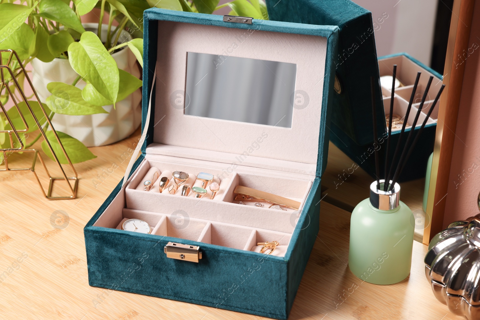 Photo of Elegant jewelry box with beautiful bijouterie and expensive wristwatch on wooden table