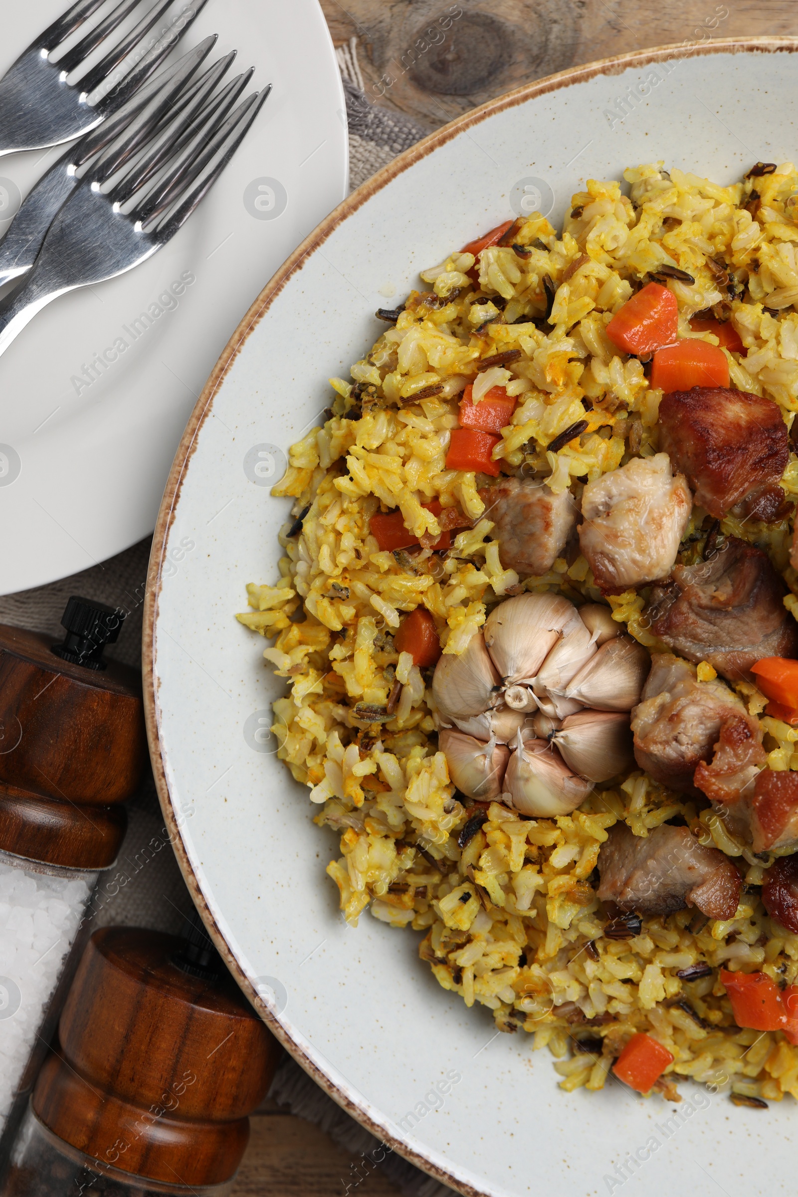 Photo of Delicious pilaf on wooden table, flat lay