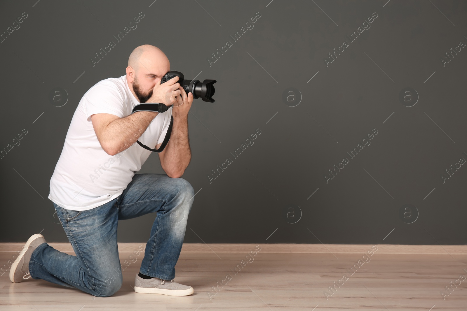 Photo of Male photographer with camera near grey wall