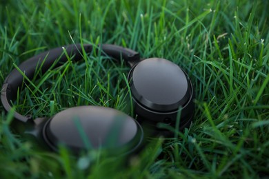 Black wireless headphones on green grass outdoors, closeup