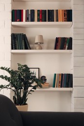 Photo of Shelves with different books and decor on light wall
