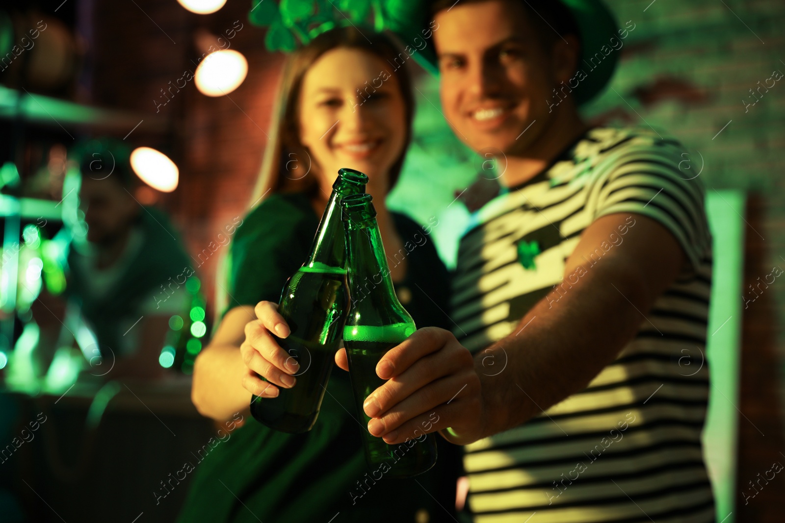 Photo of Couple with beer celebrating St Patrick's day in pub, focus on hands