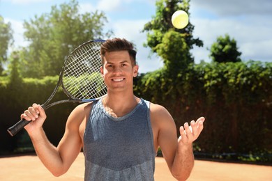 Photo of Happy man with tennis racket and ball on court