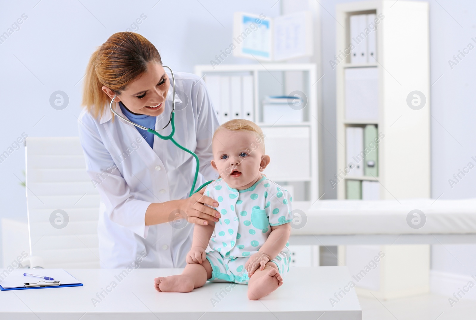 Photo of Children's doctor examining baby with stethoscope in hospital. Space for text