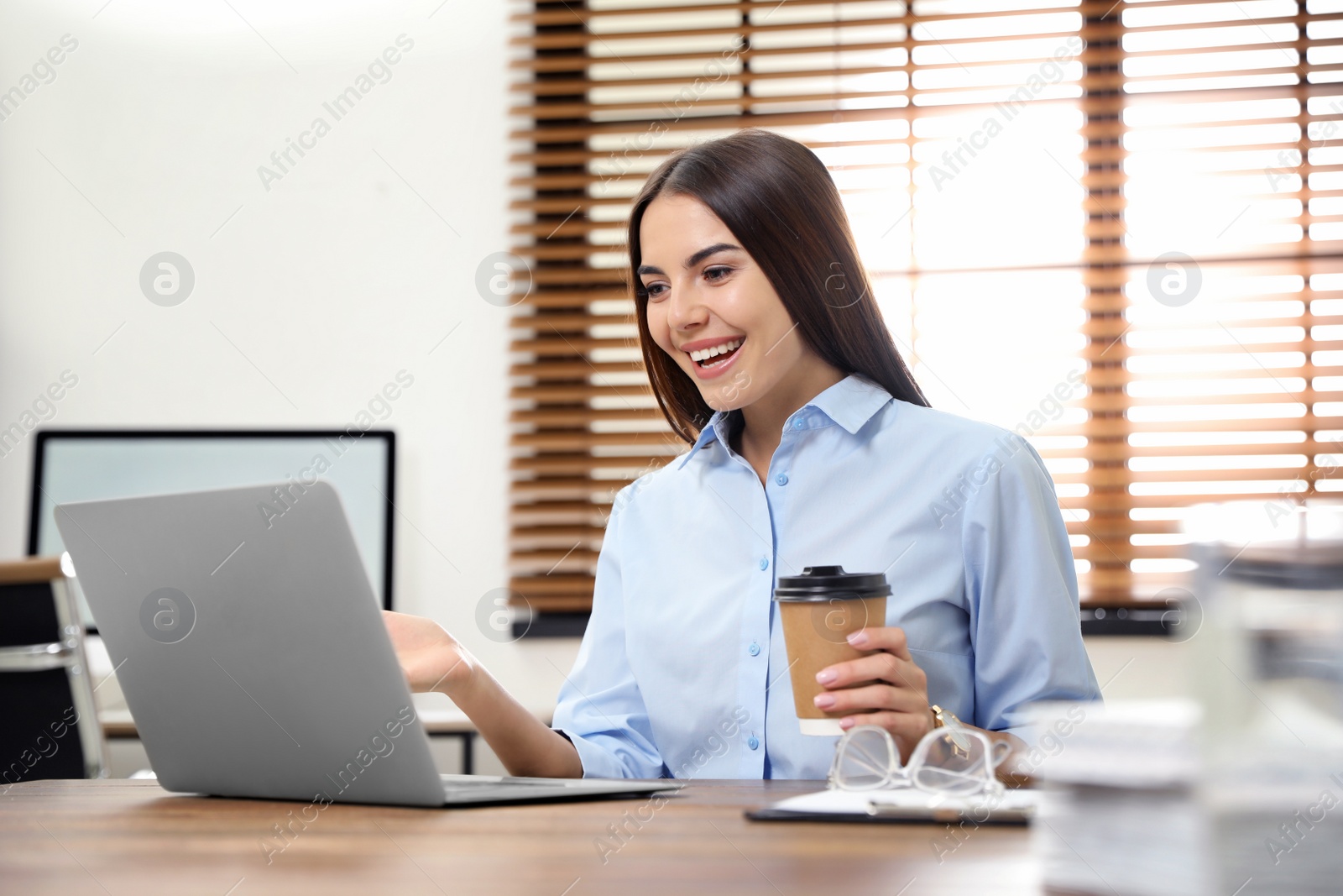 Photo of Young woman using video chat on laptop in home office