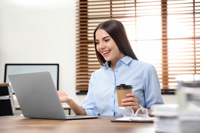 Young woman using video chat on laptop in home office