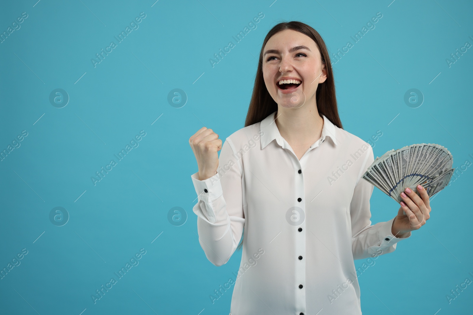 Photo of Excited woman with dollar banknotes on light blue background