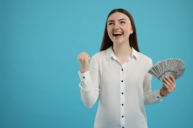 Photo of Excited woman with dollar banknotes on light blue background