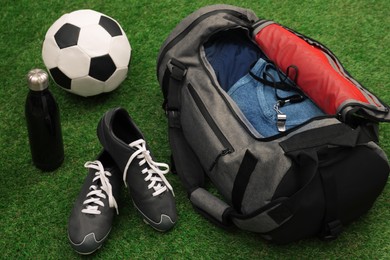Photo of Gym bag and sports equipment on green grass