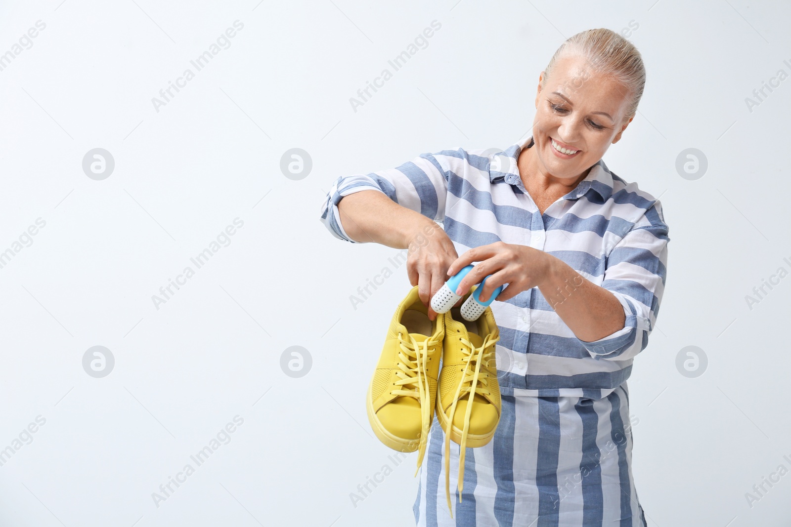 Photo of Woman putting capsule shoe freshener in footwear on white background. Space for text
