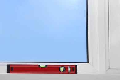 Photo of Red building level on white windowsill indoors, space for text