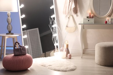 Photo of Large mirror with light bulbs and dressing table in stylish room. Interior design