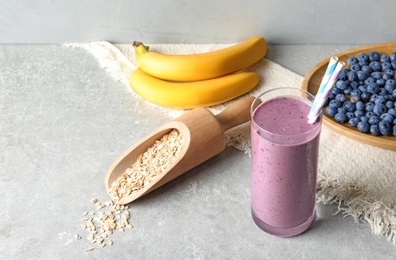 Glass with blueberry smoothie on grey table