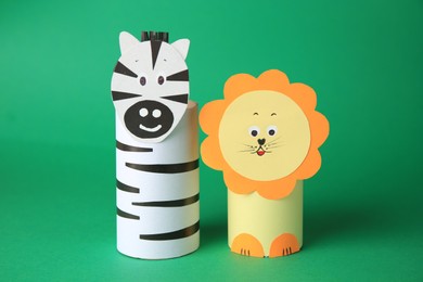 Photo of Toy lion and zebra made from toilet paper hubs on green background. Children's handmade ideas