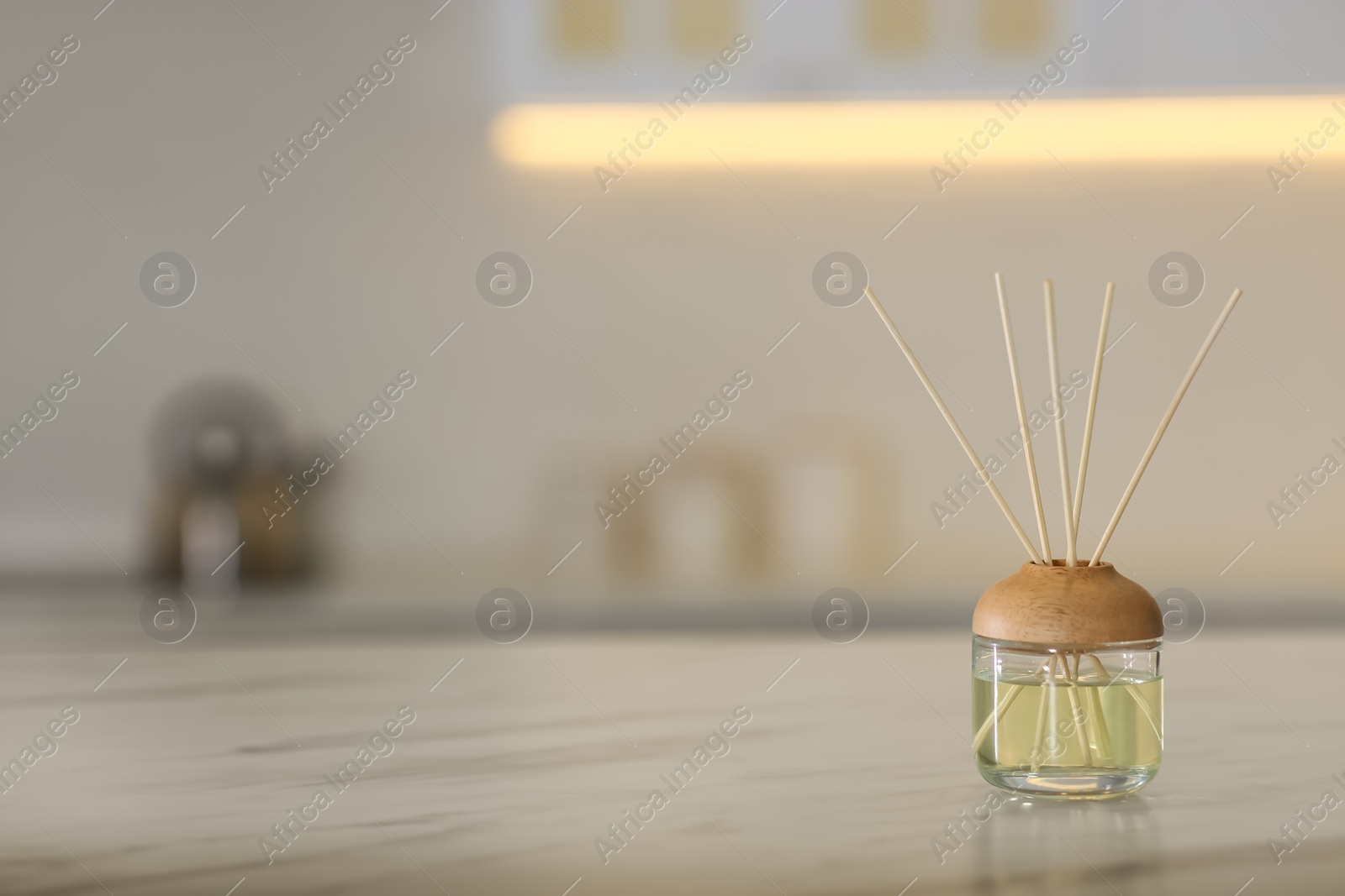 Photo of Aromatic reed air freshener on table indoors. Space for text