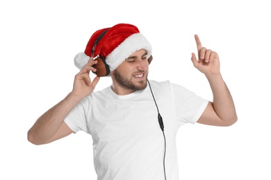 Young man in Santa hat listening to Christmas music on white background