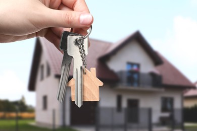 Image of Woman holding keys near house outdoors, closeup