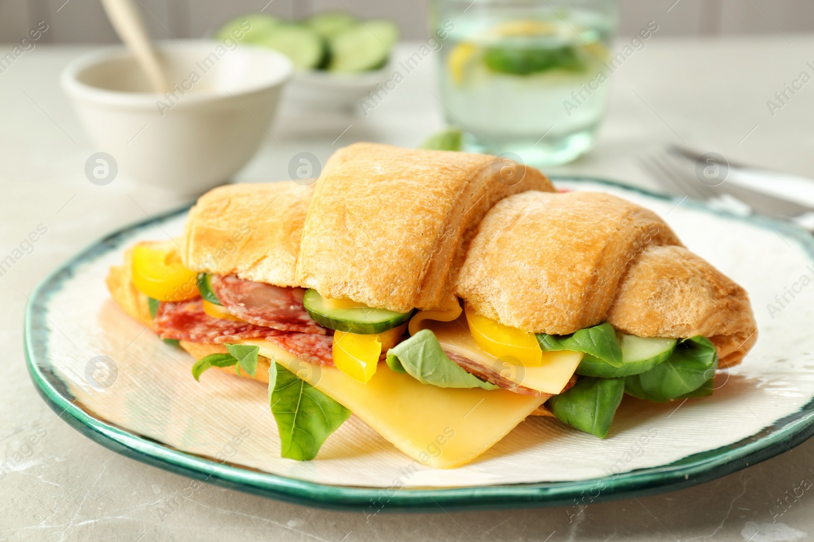 Photo of Tasty croissant sandwich with salami on table