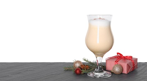 Photo of Delicious eggnog in glass, gift box and Christmas decor on grey table against white background, space for text