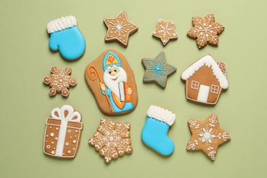 Tasty gingerbread cookies on light green background, flat lay. St. Nicholas Day celebration