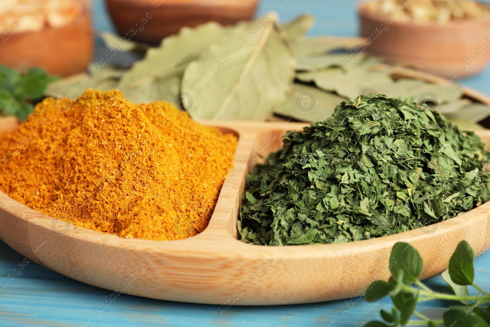 Photo of Portion plate with different spices on light blue wooden table, closeup