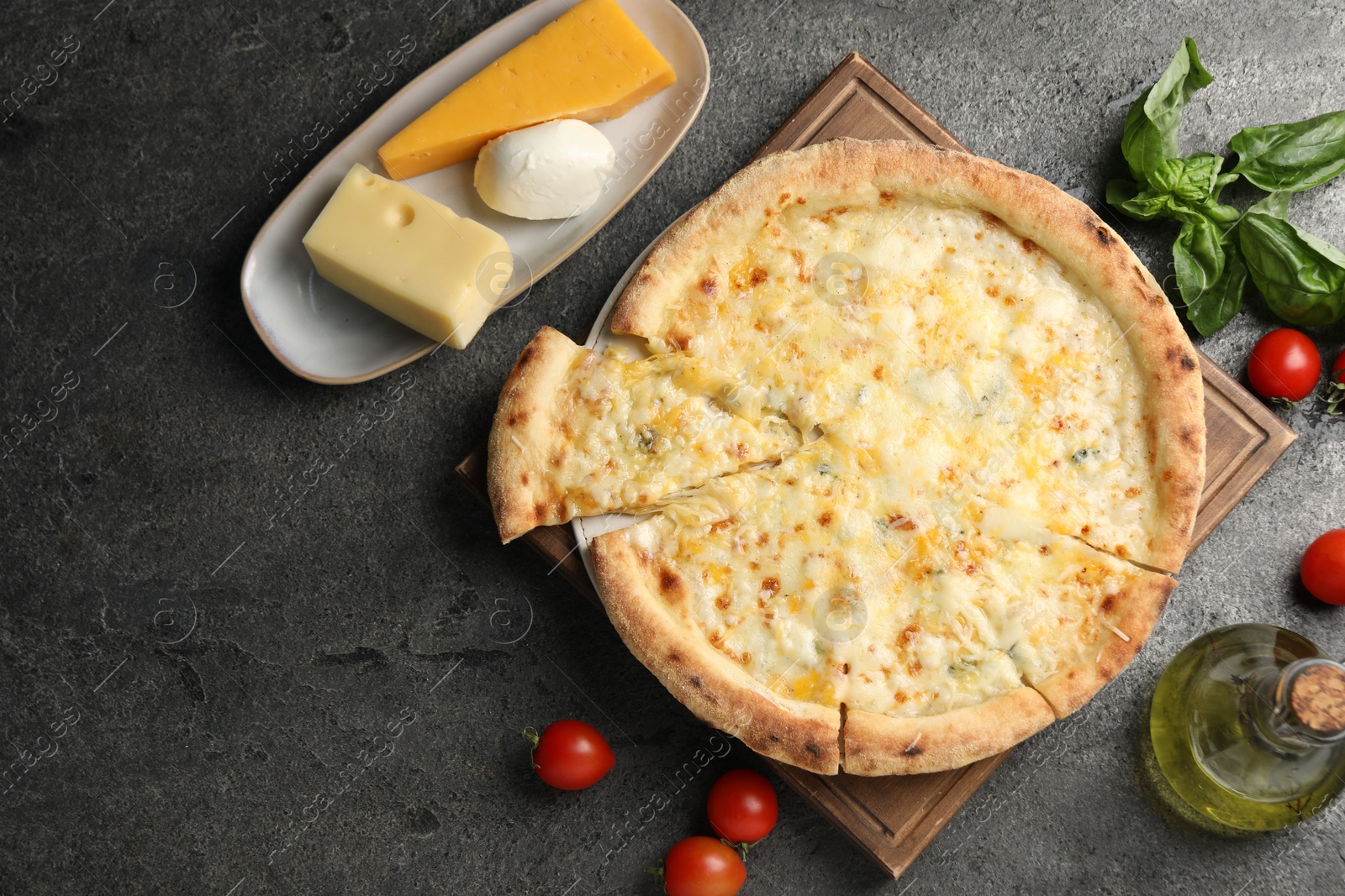 Photo of Delicious cheese pizza and ingredients on dark grey table, flat lay. Space for text