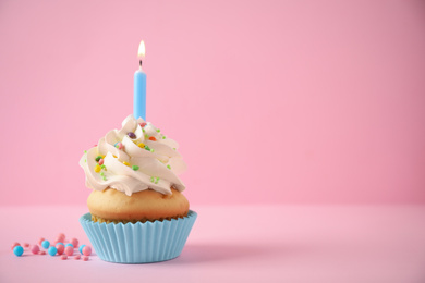 Photo of Delicious birthday cupcake with candle on pink background. Space for text