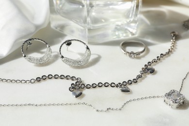 Photo of Metal chains and other different accessories on white table, closeup. Luxury jewelry