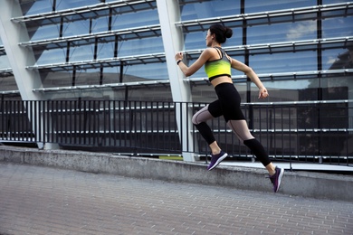 Photo of Beautiful sporty young woman running on street