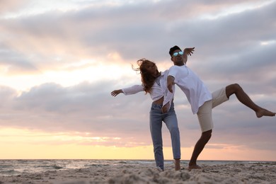 Photo of Happy couple dancing on beach at sunset