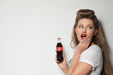 Photo of MYKOLAIV, UKRAINE - NOVEMBER 28, 2018: Young woman with bottle of Coca-Cola on white background, space for text