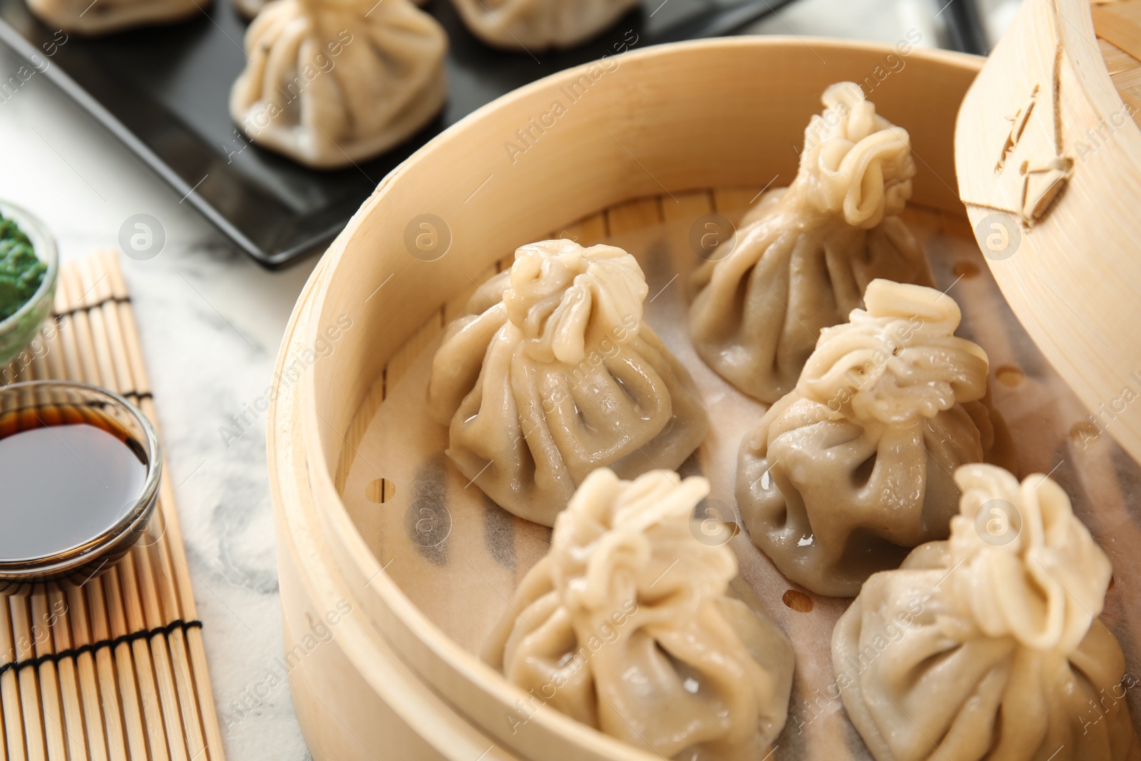 Photo of Bamboo steamer with tasty baozi dumplings on table, closeup