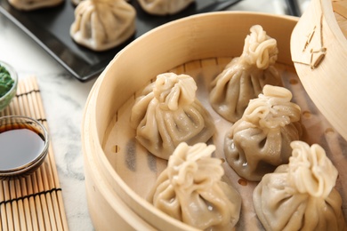 Photo of Bamboo steamer with tasty baozi dumplings on table, closeup