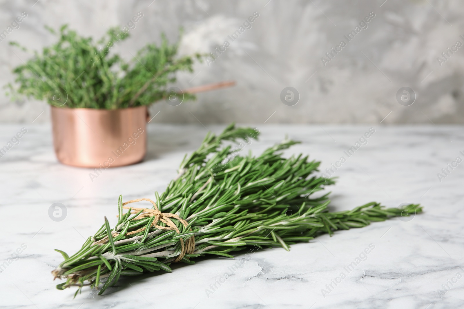 Photo of Bunch of fresh rosemary on marble table. Aromatic herbs