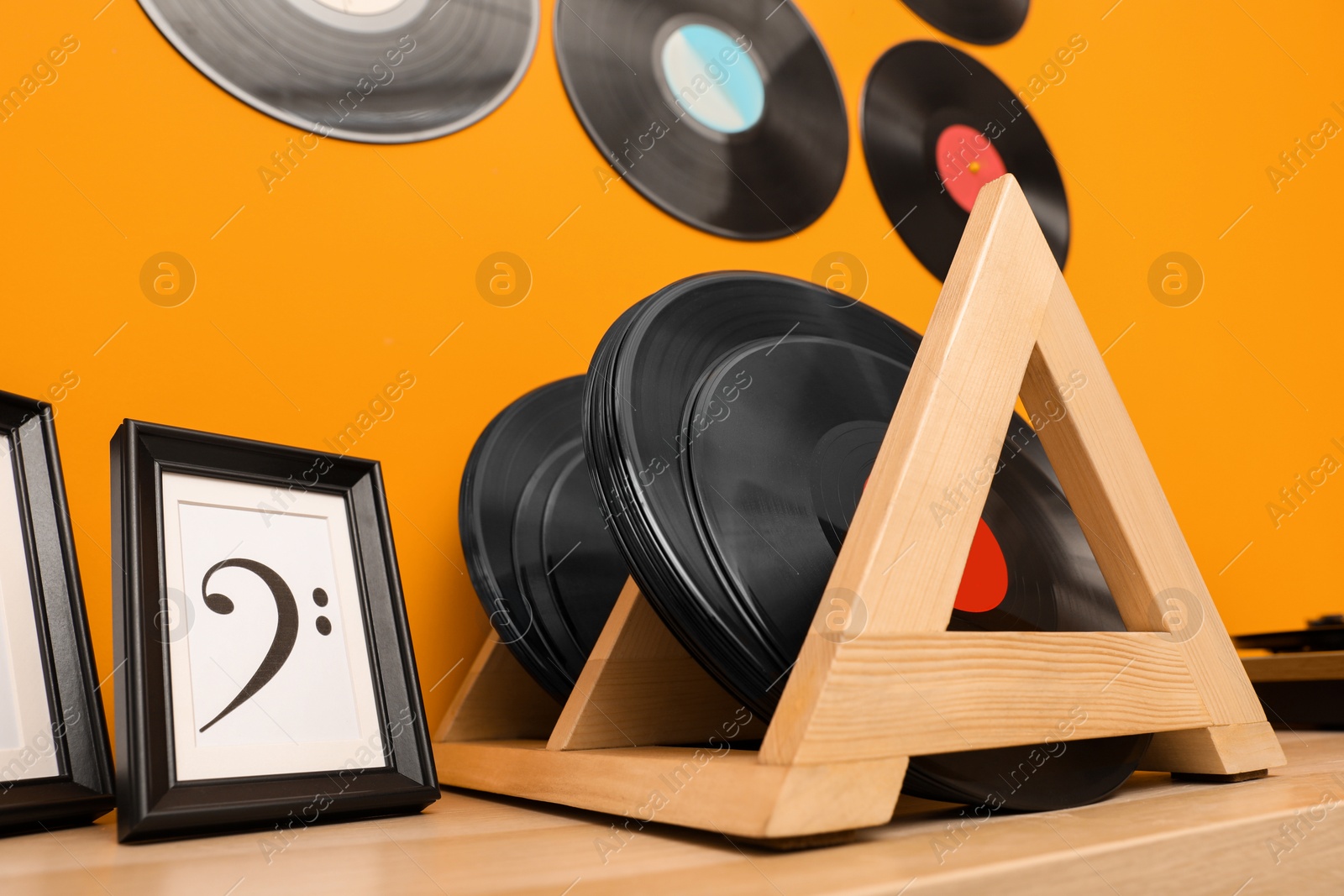 Photo of Vinyl records and pictures on wooden table near orange wall