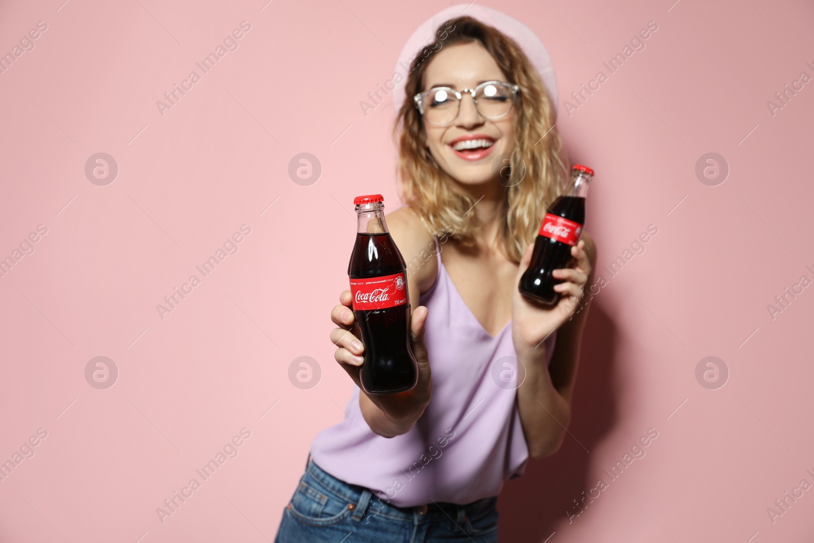 Photo of MYKOLAIV, UKRAINE - NOVEMBER 28, 2018: Young woman with bottles of Coca-Cola on color background