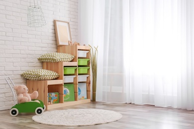 Modern eco style interior of child room with wooden crates near brick wall. Space for text